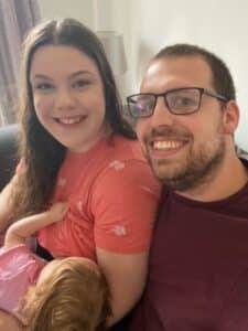 Laura Harrison breastfeeding daughter as husband sits beside her