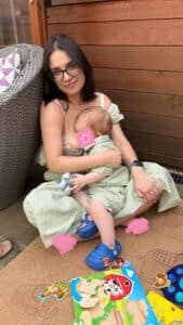 Nadine breastfeeding her toddler on the floor
